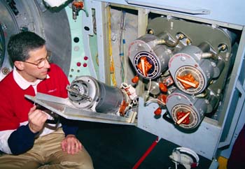 S96-09886 - Astronaut Jay Apt looking at Solid Fuel Oxygen Generator like the one that caught fire on Mir .