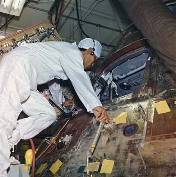 Landing and Recovery Division Systems Engineer John K. Hirasaki removing equipment and decontaminating of the interior of the Apollo 11 spacecraft inside the Lunar Receiving Lab.