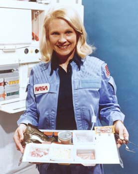 Astronaut Rhea Seddon in the Orbital Flight Test galley with Shuttle food tray.