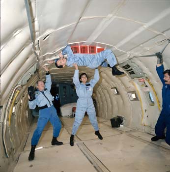 Indonesian Payload Specialists Taufik Akbar (top) and Pratiwi Sudarmono training in Zero-Gravity on the KC-135 aircraft.  Terry Slezak is on the left holding the camera.