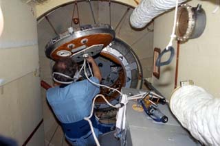 Vinogradov opens the hatch in the Docking Module on the Mir