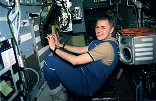 Astronaut Shannon Lucid types data into a laptop computer in the Priroda module. Behind her is the microgravity glovebox.