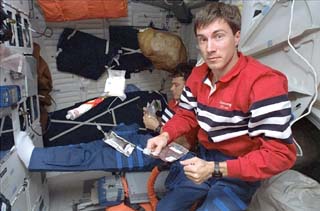 Krikalev holds a food packet on the middeck
