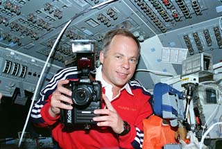 Soloyvev in shuttle's flight deck with camera