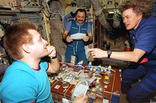 Lucid talks to Usachev  (back) and Onufriyenko (front) at the work table in Mir's Base Block