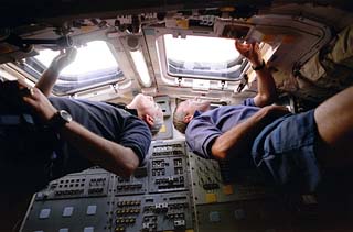 Wilcutt & Readdy looking out overhead windows in shuttle's flight deck