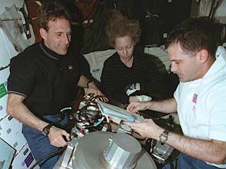 Linenger, Ivins, and Wisoff prepare equipment in hab