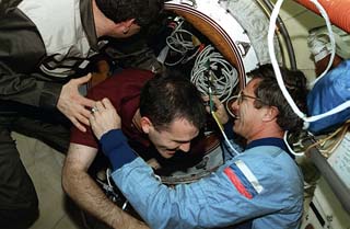 View in the Docking module of Korzun (left) and mission specialist John Blaha (right) greeting STS-81 mission specialist Jeff Wisoff as he enters. 