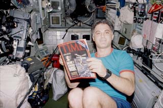 Mir 24 crewmember David Wolf reads a Time magazine, bearing the headline "How I Survived Mir: Astronaut Michael Foale describes his most harrowing day in space," while floating on the Base Block of the Mir Space Station during NASA 6.